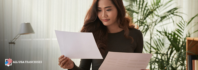 Franchisee Woman Comparing Franchise Rights Document vs. Franchise Agreement Document