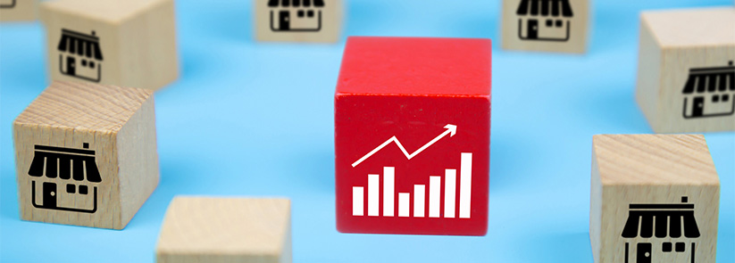 Wooden Cubes on a Table Representing Businesses and One Red Wooden Cube With a High Growth Graphic Representing a Franchise