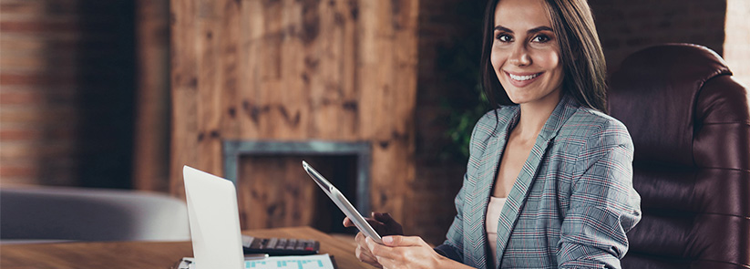 Female Franchise Owner With a Tablet and Laptop in Her Office